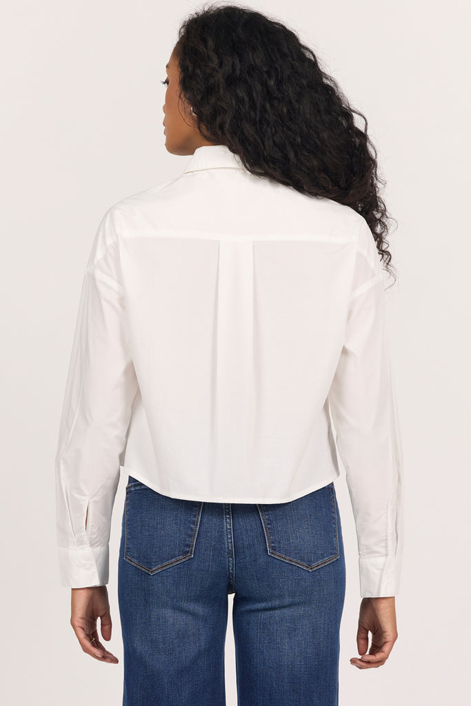 back of woman in white cropped blouse against white background