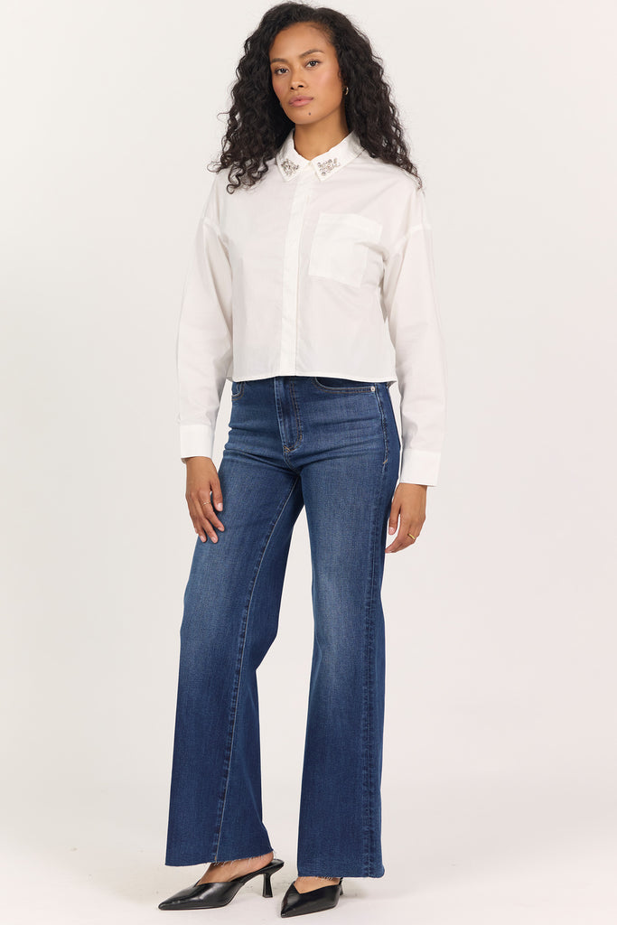 woman in white cropped blouse with rhinestones on the collar against white background