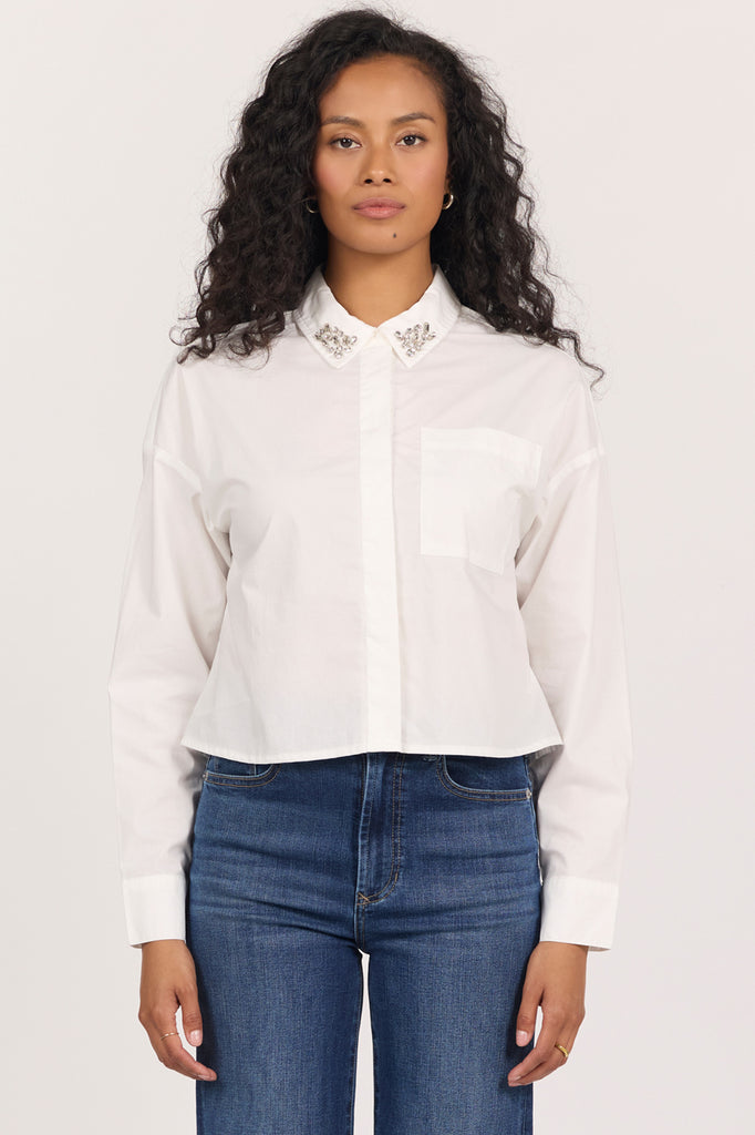 woman in white cropped blouse with rhinestones on the collar against white background