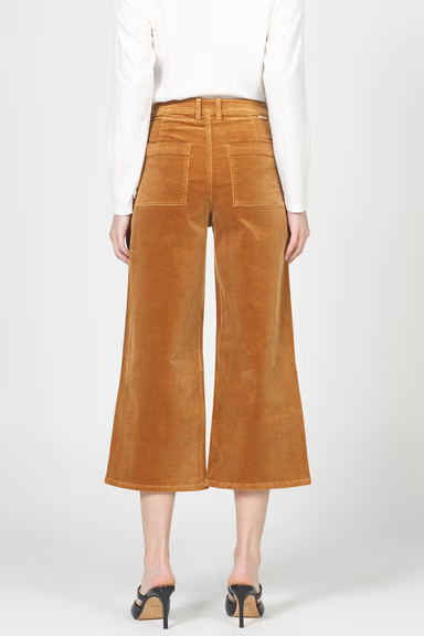 Brown corduroy pants worn by a person on a white background