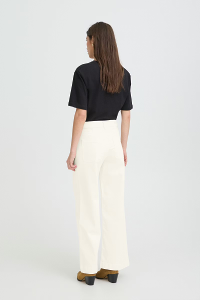 Person wearing a black top and white pants on a white background