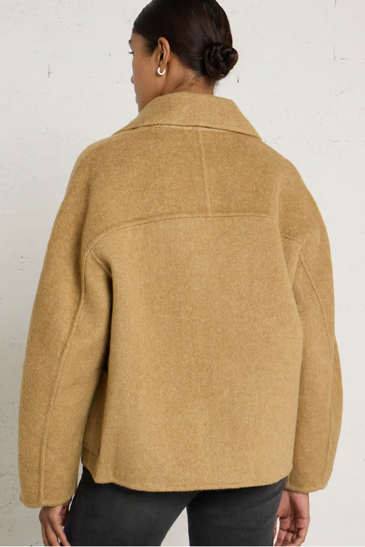 woman in camel coat against white background