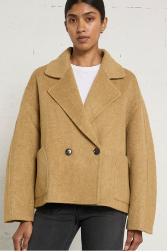 woman in camel coat against white background
