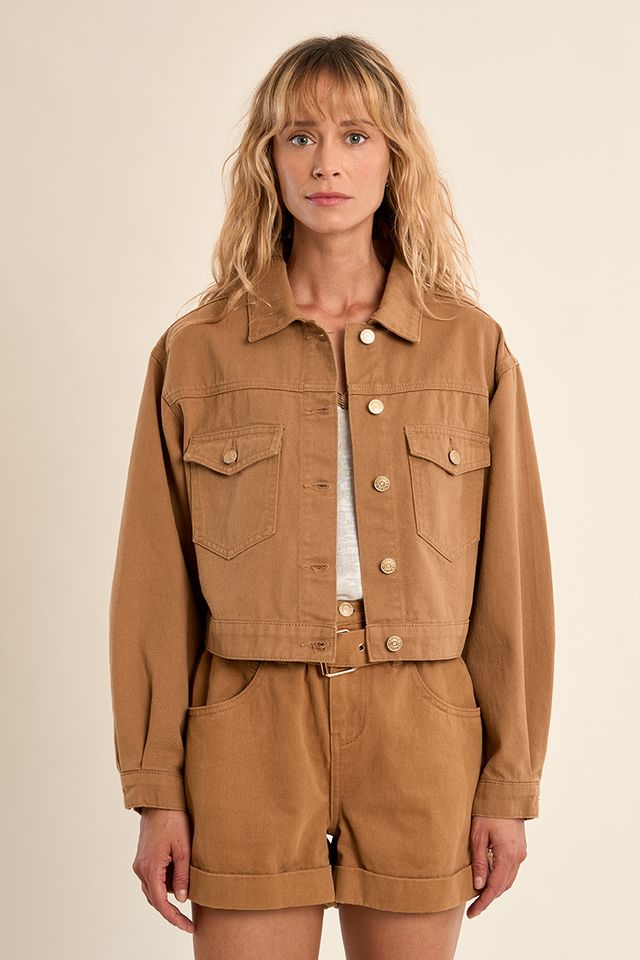 Woman wearing a brown jacket and shorts set on a beige background