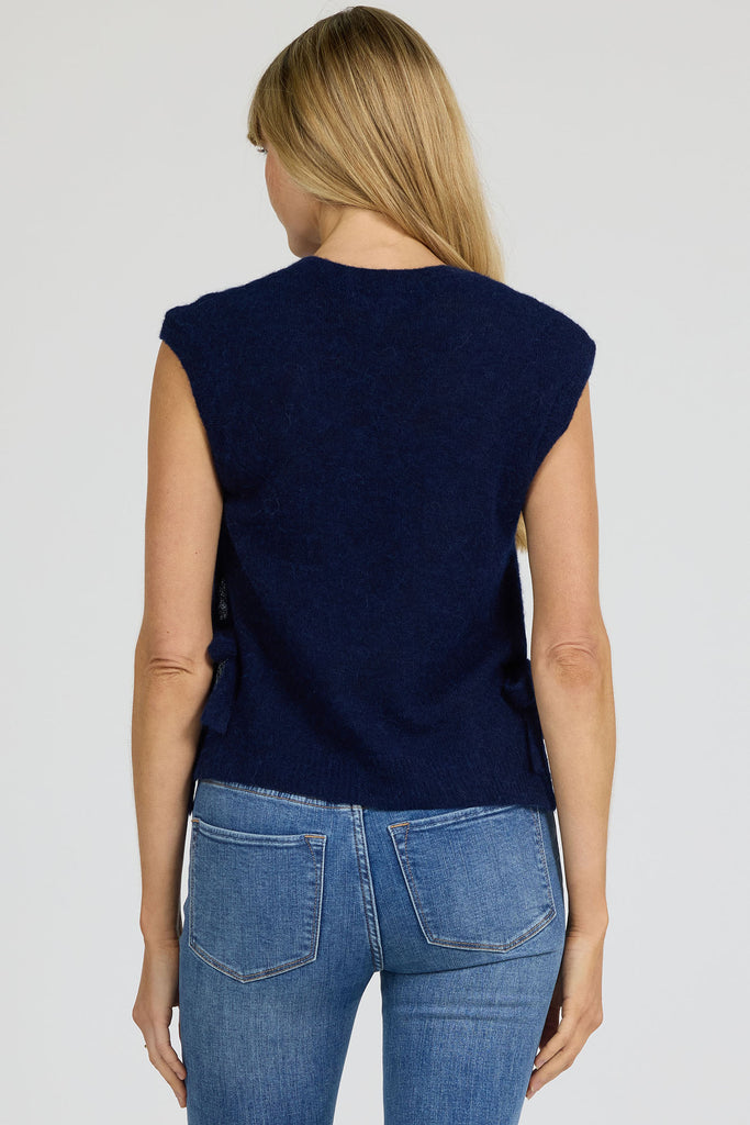 Woman wearing a navy sleeveless top and blue jeans on a white background