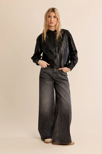 woman in cropped leather jacket and washed black jeans against a white background