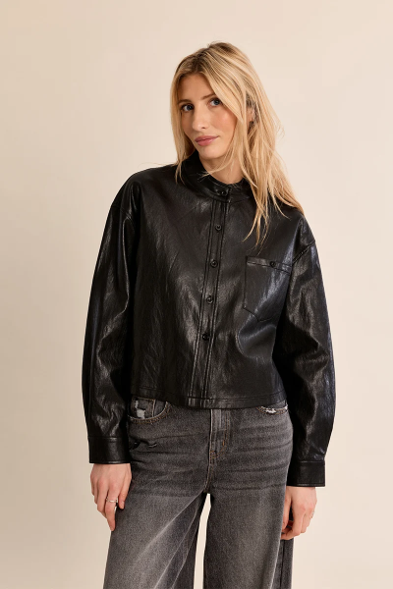woman in cropped leather jacket against a white background