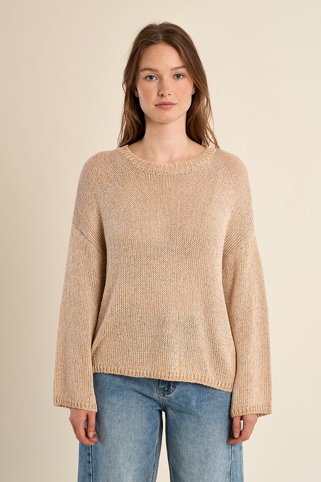Woman wearing a beige sweater and blue jeans on a beige background