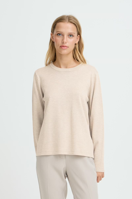 Woman wearing a beige sweater and pants on a white background