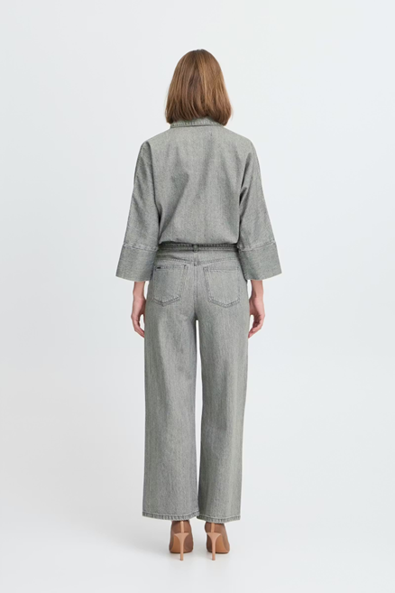 Person wearing a gray checkered shirt and wide-leg jeans on a white background