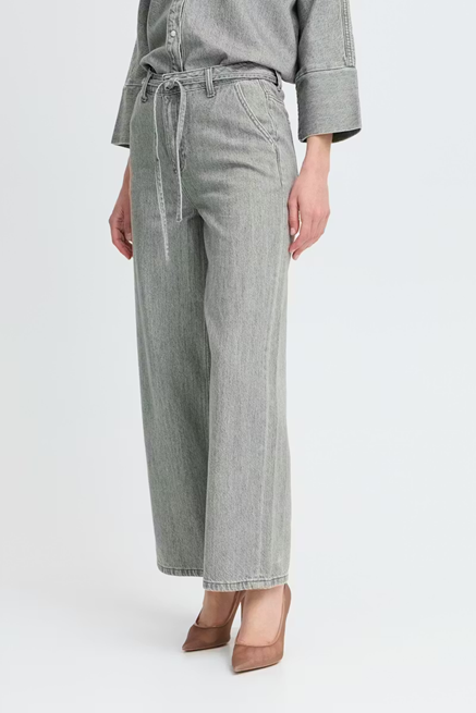 Person wearing gray wide-leg jeans and a matching top on a white background