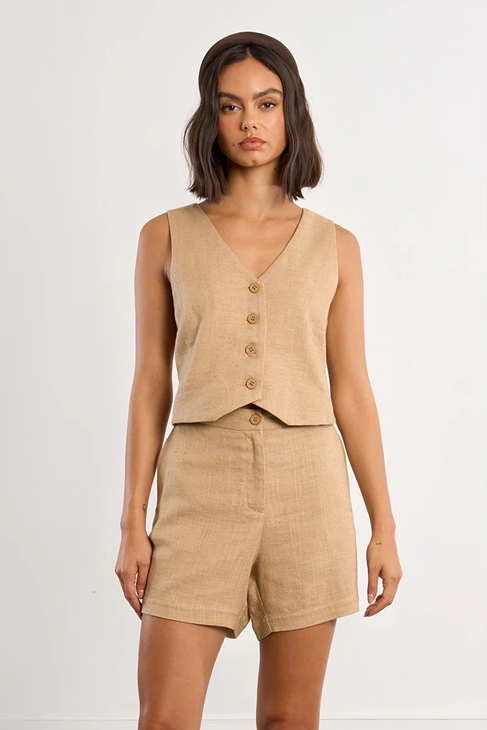 Woman wearing a beige sleeveless top and shorts set on a white background
