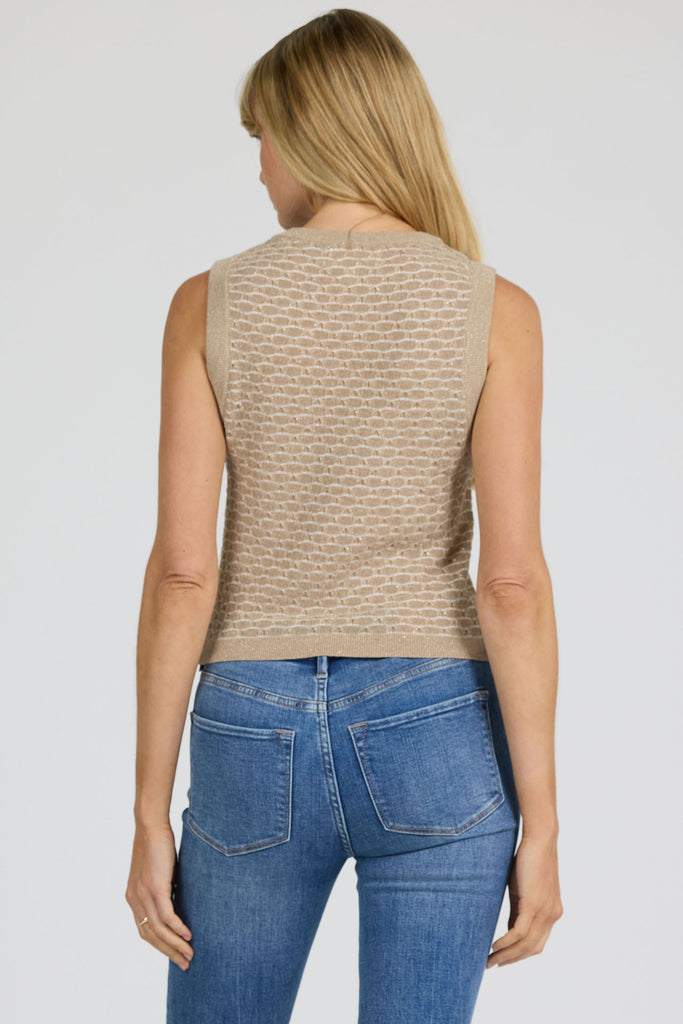 Woman wearing a beige sleeveless top and blue jeans on a plain background