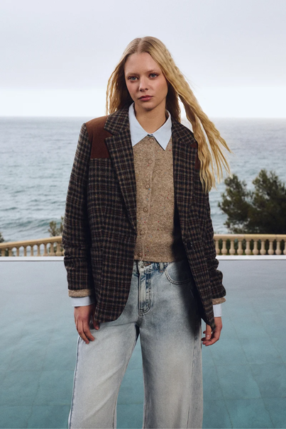 woman in plaid jacket and light pants standing outside