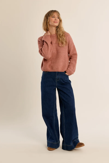 woman in pink sweater and jeans against a white background