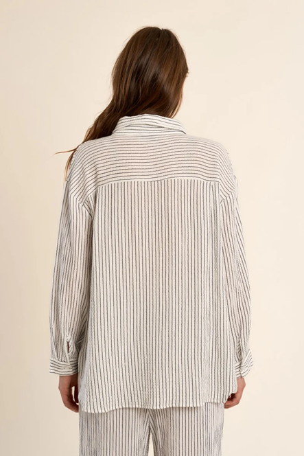 Person wearing a striped shirt and pants on a beige background