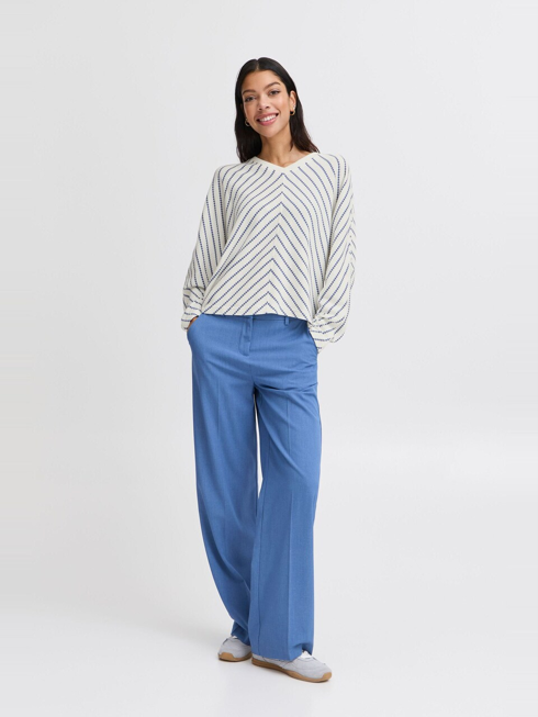 woman in blue and white striped top and blue jeans against white background