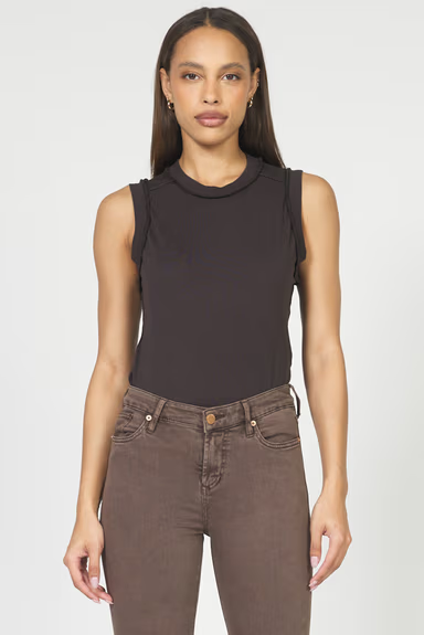 Woman wearing a black sleeveless top and brown pants on a white background