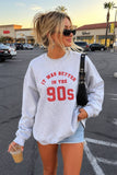 Girl wearing a sweatshirt and shorts holding a coffee in a parking lot 