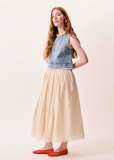 Woman wearing a denim top and beige skirt on a white background