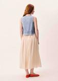 Woman wearing a light blue denim vest over a beige dress on a white background