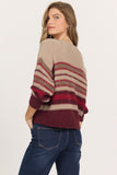 woman in v-neck, striped sweater and jeans against white background