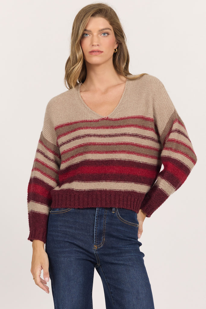 woman in v-neck, striped sweater and jeans against white background