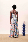 Woman wearing a floral dress standing in front of a blue vase on a wooden floor.