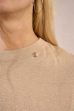 Close-up of a beige textured fabric with a button, worn by a person.