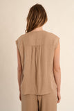 Woman wearing a beige sleeveless top and pants against a beige background