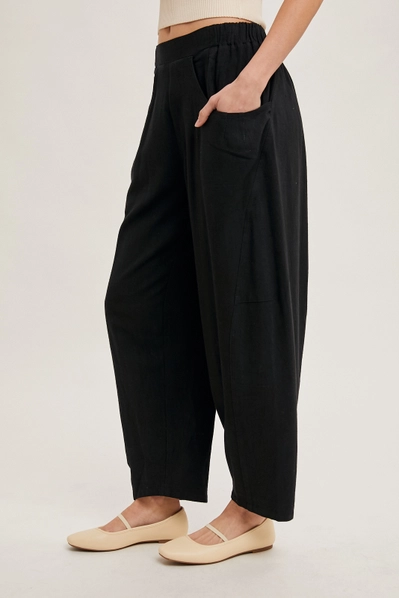 black barrel pants with hands in pocket against white background