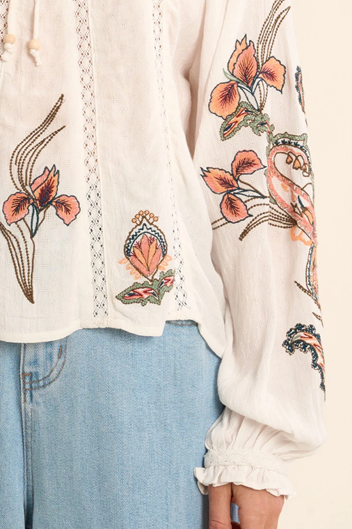 White blouse with floral embroidery paired with light blue jeans.
