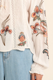 White blouse with floral embroidery paired with light blue jeans.