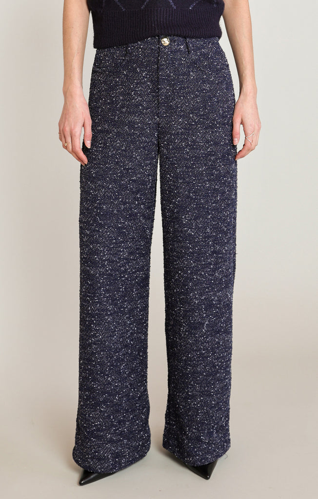 Person wearing navy blue patterned pants on a plain background