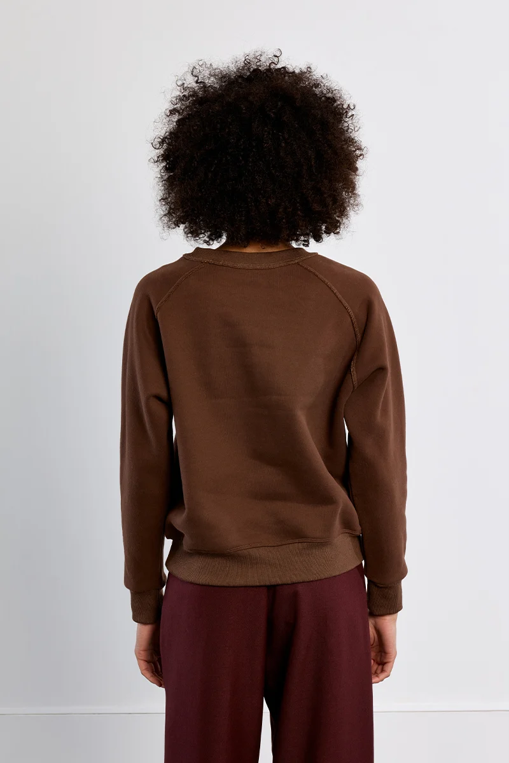back of model wearing a brown sweatshirt against white background