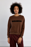 model wearing a brown sweatshirt with the word BRUNCH on front