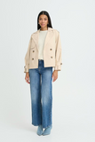 Woman wearing a beige jacket and blue jeans on a white background