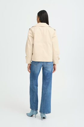 Person wearing a beige jacket and blue jeans on a white background