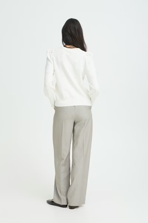 Person wearing a white sweater and light gray pants on a white background