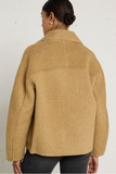 woman in camel coat against white background
