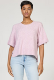 Woman wearing a light pink sweater and light blue jeans on a plain background