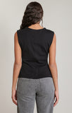 back of woman in black sleeveless shirt and jeans against white wall