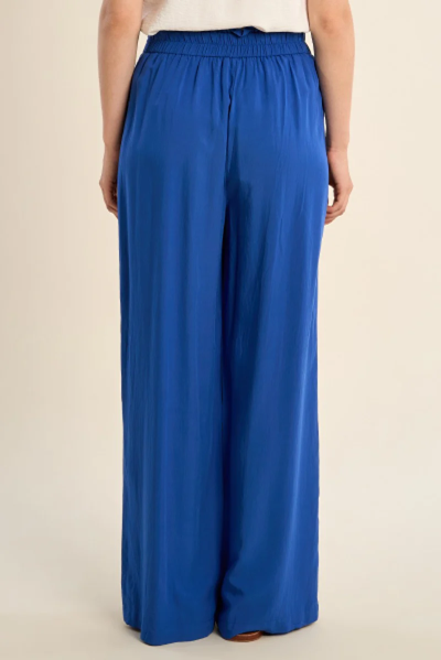 Blue wide-leg pants worn by a person on a beige background
