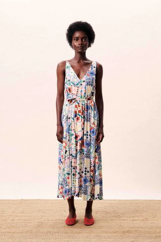 Woman wearing a colorful floral dress against a plain background