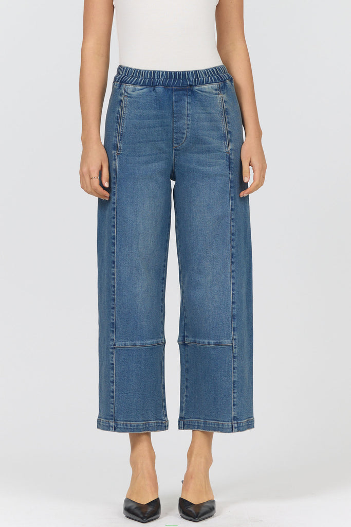 Person wearing blue denim wide-leg pants on a white background