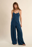 Woman wearing a blue denim jumpsuit on a beige background