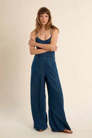 Woman wearing a blue denim outfit on a beige background
