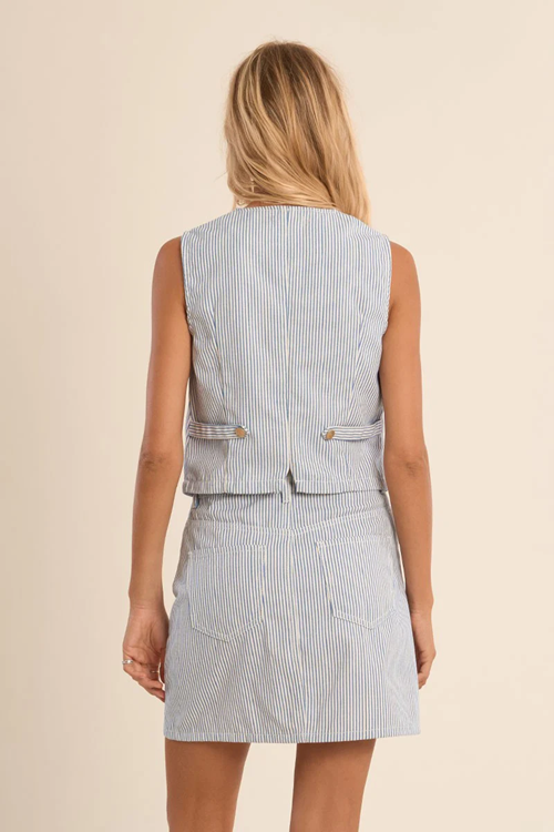 Woman wearing a light blue striped vest and skirt set on a beige background