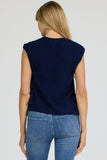 Woman wearing a navy sleeveless top and blue jeans on a white background