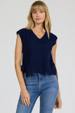 Woman wearing a navy blue sleeveless top and blue jeans on a white background
